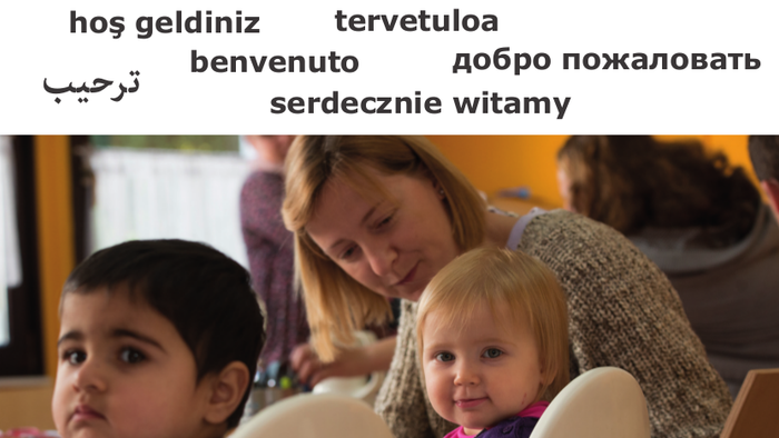 Kinder im Vordergrund mit Frau am Tisch