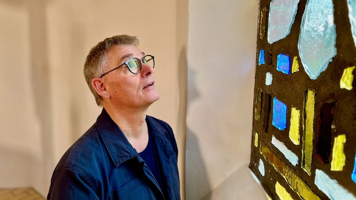 Mand ser opadad til et farverigt glasvindue.