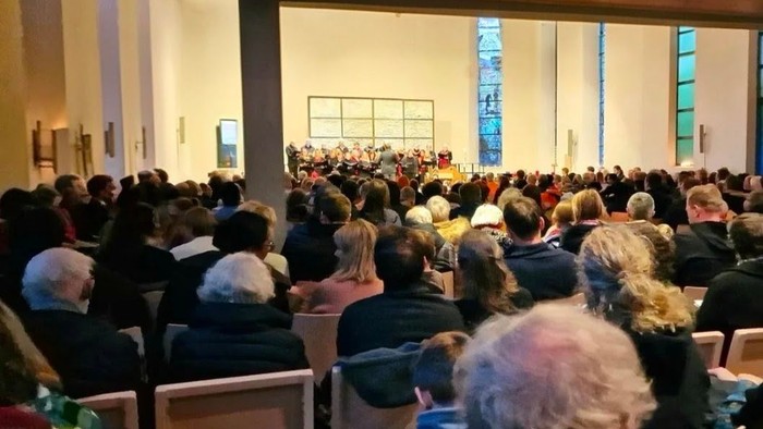 Ein festlicher Gottesdienst mit einem vollbesetzten Publikum und goldenen Sternendekorationen über den Köpfen.