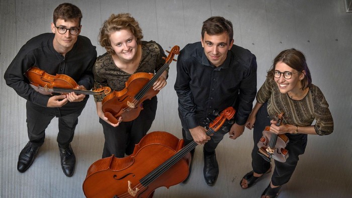 Fire musikere poser med strygeinstrumenter.