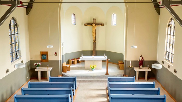 Kleine Kirche mit blauen Bänken und Kreuz im Altarbereich