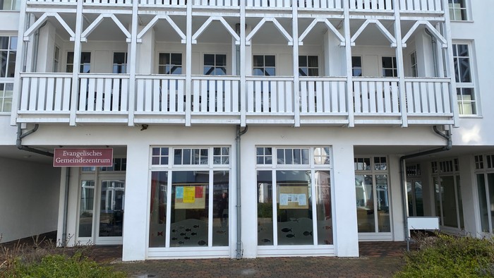 Das Gebäude hat weiße Balkone und große Fenster.