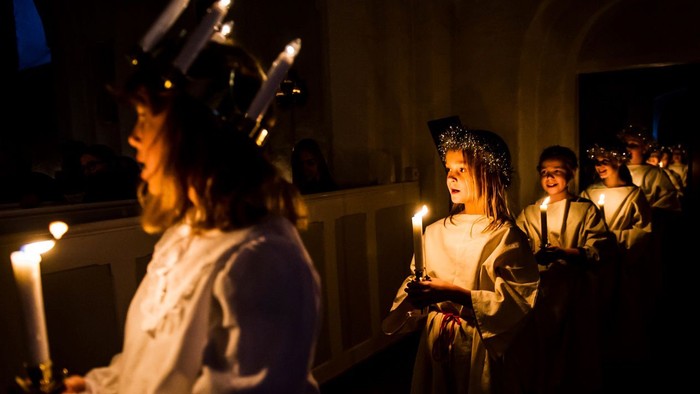 En gruppe børn med lysekøn i en mørk kirke.