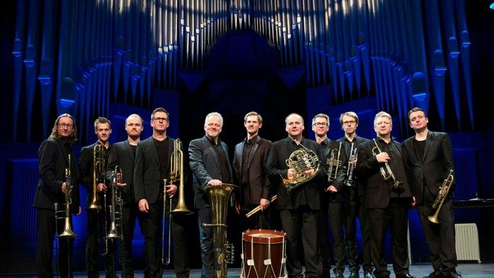 Et messingensemble optræder på scenen foran en stor orgelbaggrund.