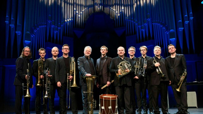 Et messingensemble optræder på scenen foran en stor orgelbaggrund.