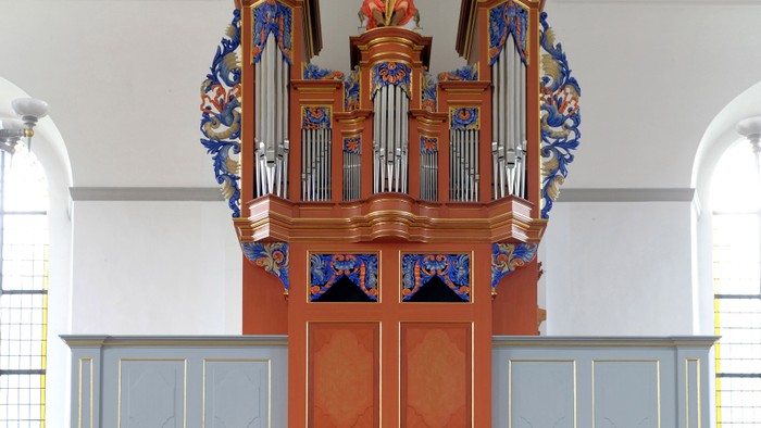 Orgel in Kirche mit farbenfroher Dekoration und Holzgehäuse