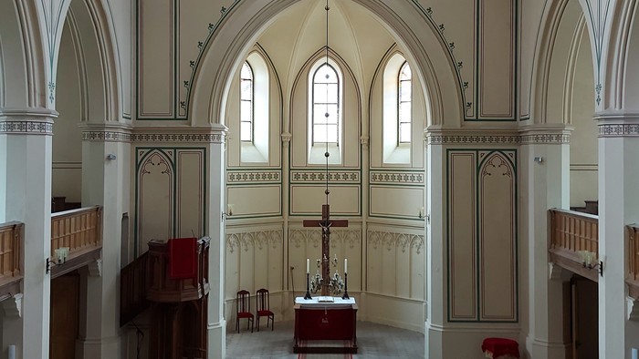 Großzügige Kirche mit hohen Bögen und Stufen zum Altar.