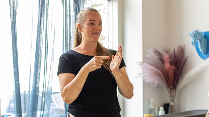 En kvinde udfører yoga i et rum med et barn og en person i forgrunden