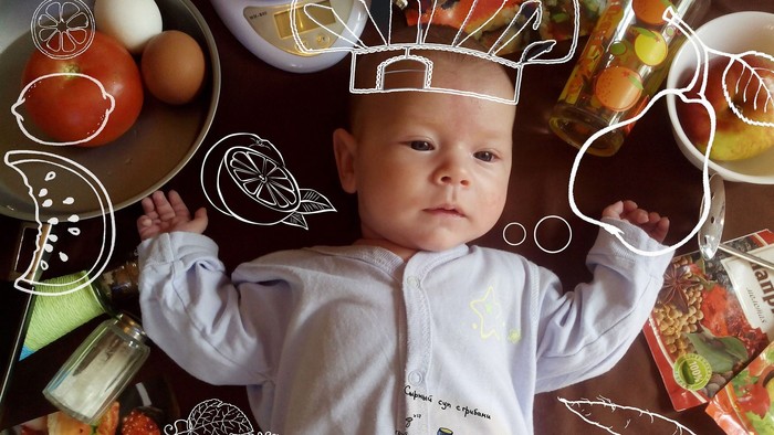 Baby i hvid køkkensmockey med køkkenudstyr og mad.