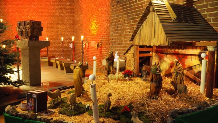 Weihnachtskrippe mit Figuren, Tieren und einer von Kerzen erleuchteten Krippenszene.