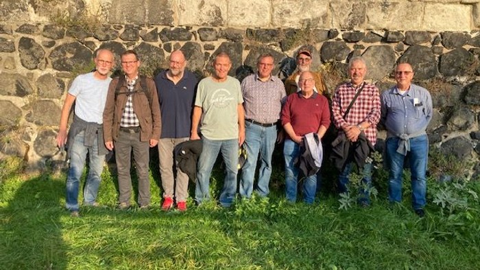 Eine Gruppe von Menschen steht vor einer Steinmauer im Freien
