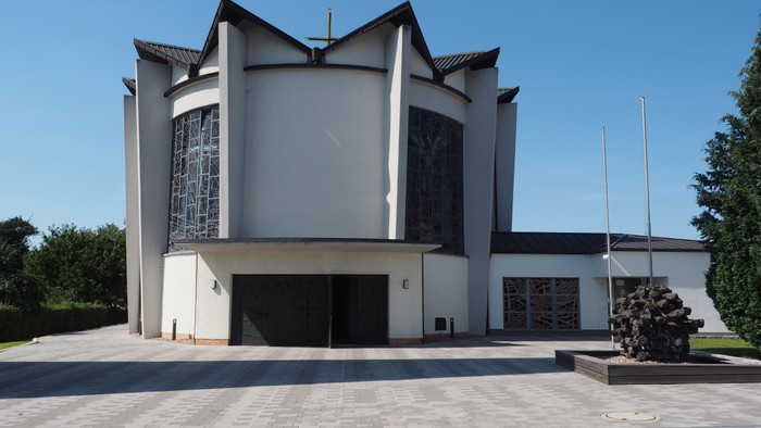 Moderne Kirche mit großen Buntglasfenstern und einem minimalistischen Architekturdesign, das eine markante Skulptur aufweist.