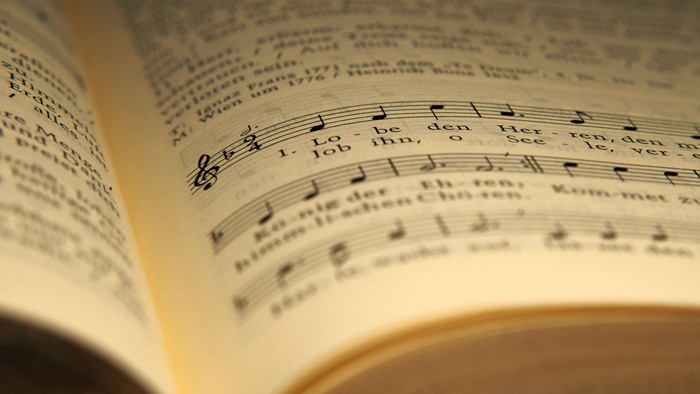 Nahaufnahme eines aufgeschlagenen Notenbuchs mit deutschen Kirchenliedtexten und Noten.