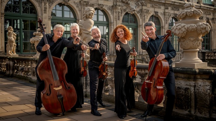 Streichquartett, das im Freien vor einem prunkvollen historischen Gebäude spielt.