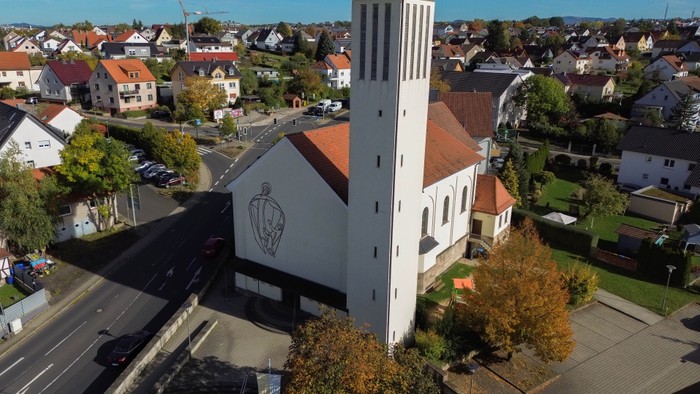 Weiße Kirche mit hohem Turm in Wohngebiet