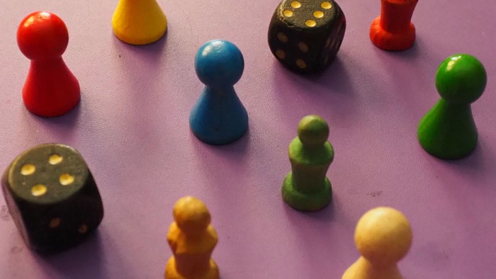 Bunte Spielsteine und Würfel auf lila Oberfläche