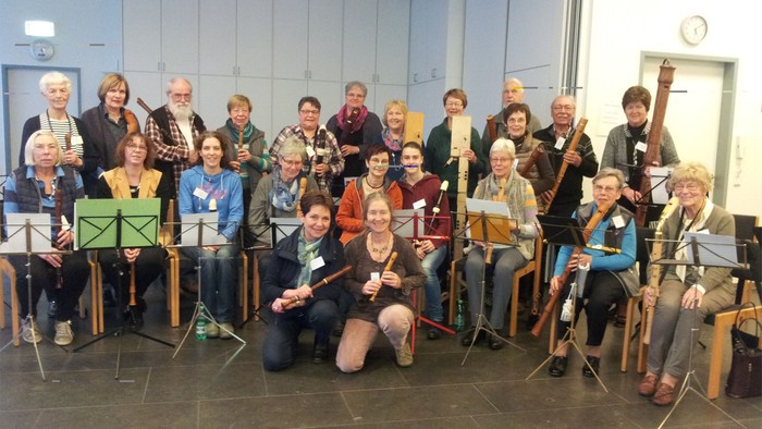 Gruppe von Personen, die mit Musikinstrumenten in einem Raum posieren