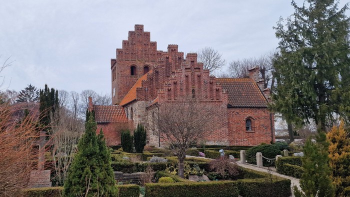 Et stort, gammelt teglsteinslot med en have og træer