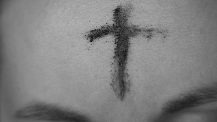 Ein Kreuz aus Asche auf der Stirn einer Person