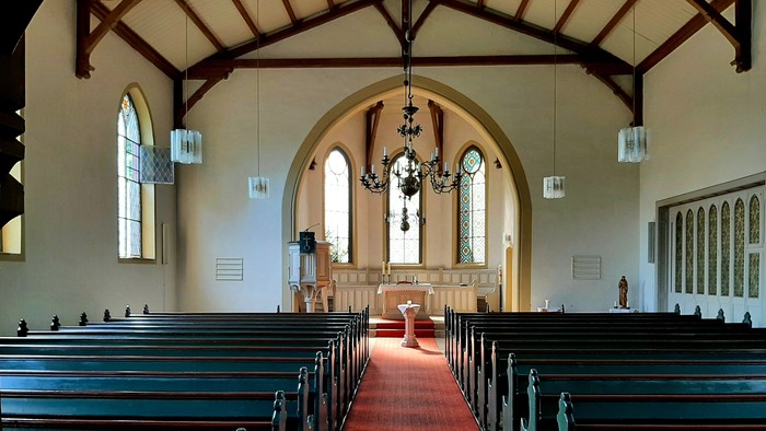 Kirchenraum, Bänke, roter Teppich, Altarraum mit Taufbecken