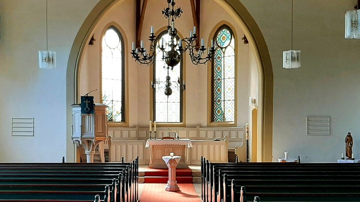 Kirchenraum, Bänke, roter Teppich, Altarraum mit Taufbecken