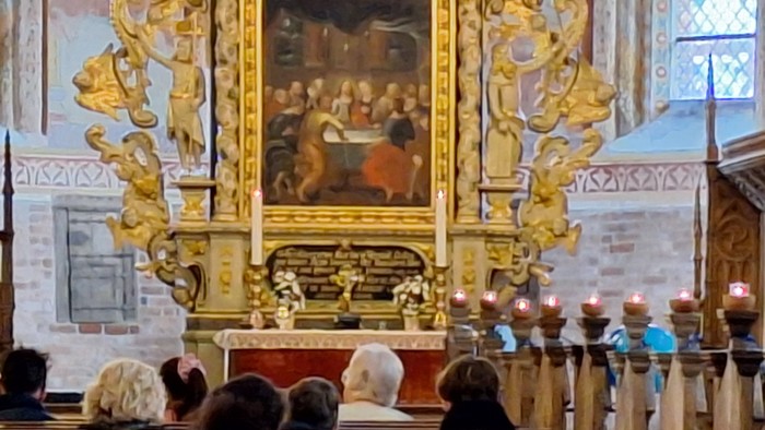 En prægtig kirkeinterior med gulddekoreret alter og maleri.