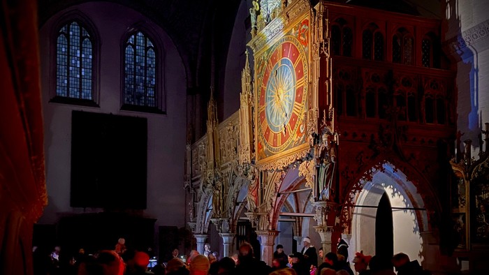 In der Kirche versammelt sich eine Menschenmenge vor einem großen, verzierten Altar.