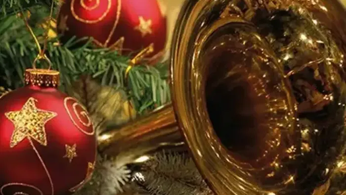 En juledekoreret greens med røde og guldornamenter og en glasbæger med chokoladepraliner.