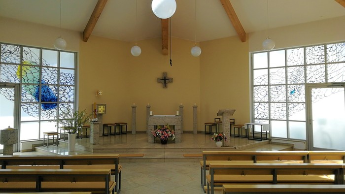Leere Kirche mit Holzbänken und großen Fenstern