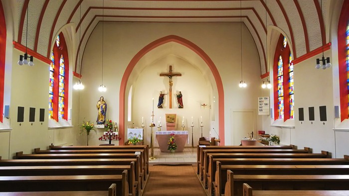 Innenraum einer Kirche mit Holzgebinden und Altar