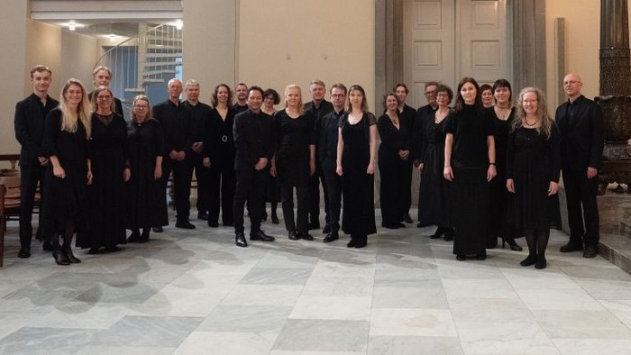 Gruppe af mennesker i sort tøj, der poserer til et foto indendørs.