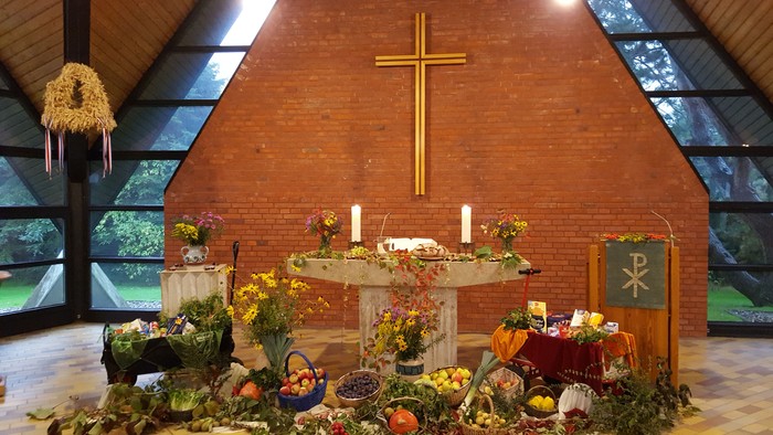 Ein festlich geschmückter Altar in einer Kirche mit Blumen, Früchten und Kerzen