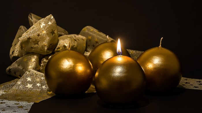 Goldene Kerzen und Christbaumkugeln auf schwarzem Hintergrund
