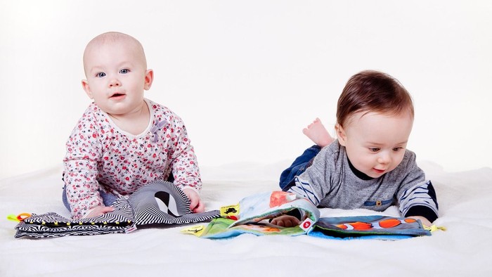 Zwei Krabbelkinder schauen sich Bilder an