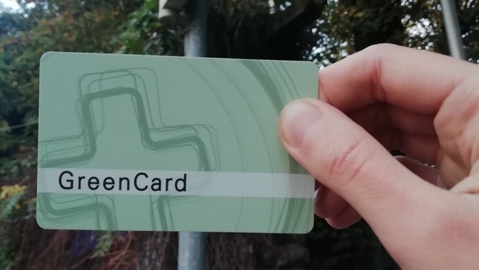 Hand hält GreenCard vor grüner Ampel