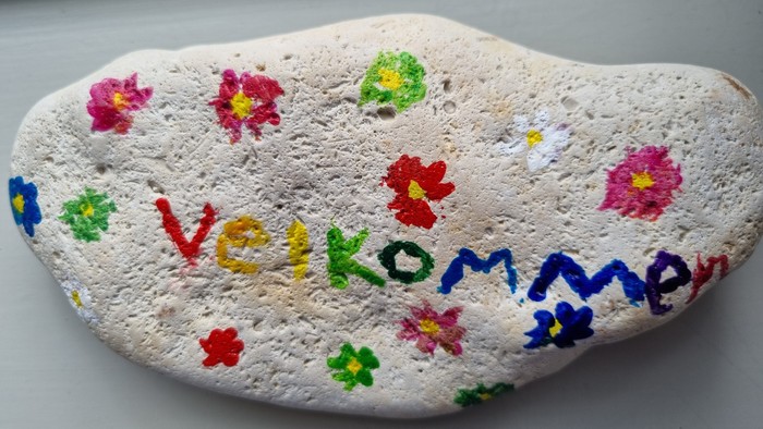 Sten med malede blomster og teksten 
