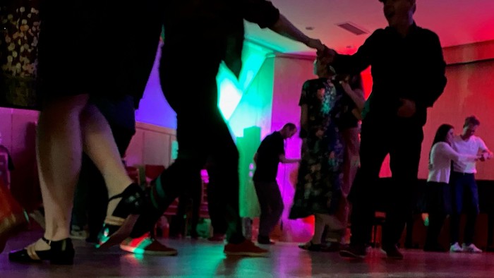 Eine Gruppe von Menschen tanzt in einem beleuchteten Raum.