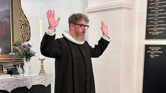 Mand i svart kapittel i kirke.