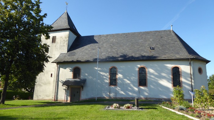 Weiße Kirche mit hohem Turm und spitzem Dach auf grünem Rasen