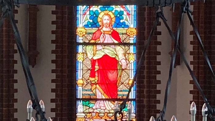 Buntes Kirchenfenster mit Darstellung von Jesus Christus in Rot und Gold
