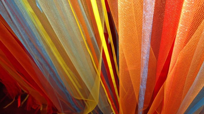 Colorful tulle fabric in various shades of orange, yellow, and blue.