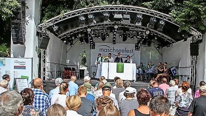 Eine Menschenmenge schaut sich eine Aufführung auf einer Bühne beim Maschseefest an.