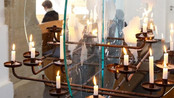 Kirchliche Kerzenleuchter vor Spiegel mit Priester