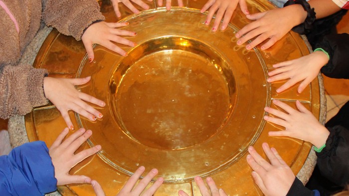 Et dåbsfad med mange Minikonfirmand-hænder på