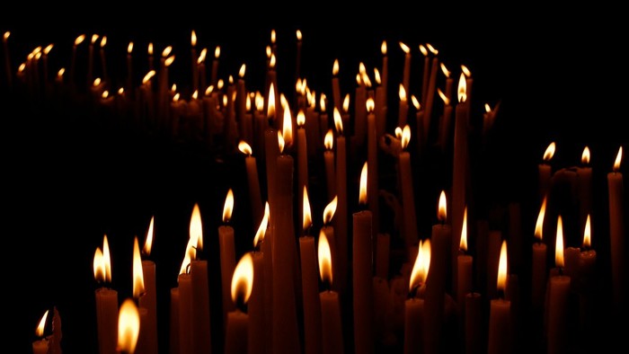 Numerous lit candles arranged closely together, creating a warm and serene atmosphere.