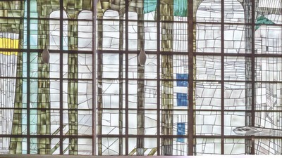 Buntes Kirchenfenster mit Holzrahmen und Sitzbank davor