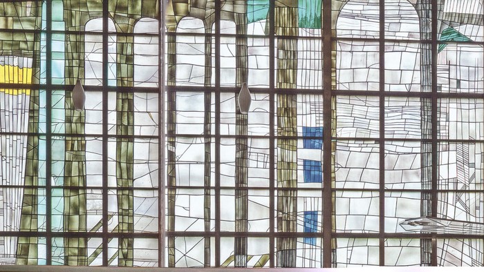 Buntes Kirchenfenster mit Holzrahmen und Sitzbank davor