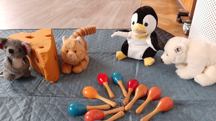 Mehrere Kuscheltiere und Maracas auf einer blauen Decke