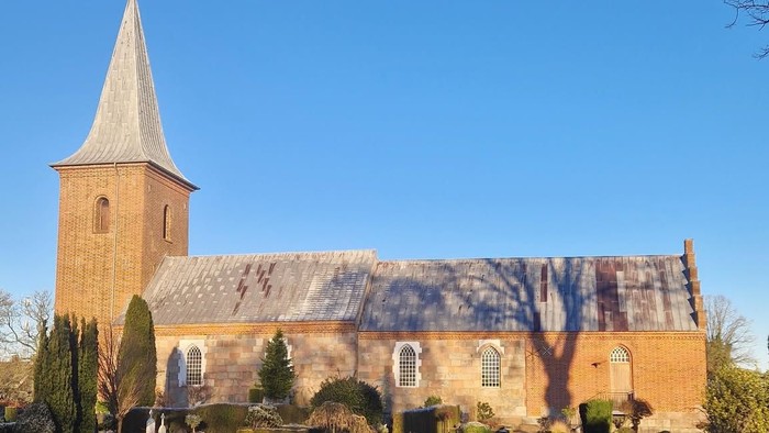En kirke med tårn og en have med buske og stier