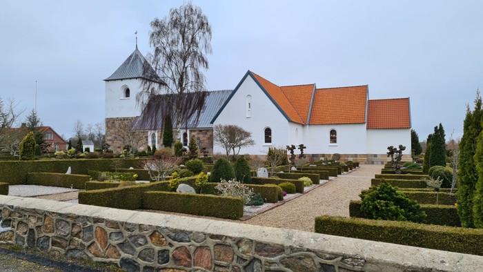 En smuk kirke med omgivelser af træer og buske